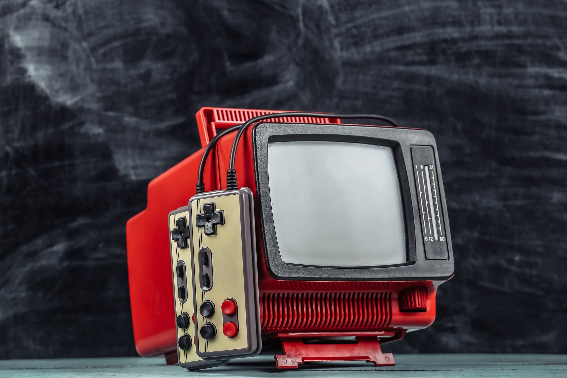 Retrogaming. Video game competition. Old TV with gamepads on blackboard background