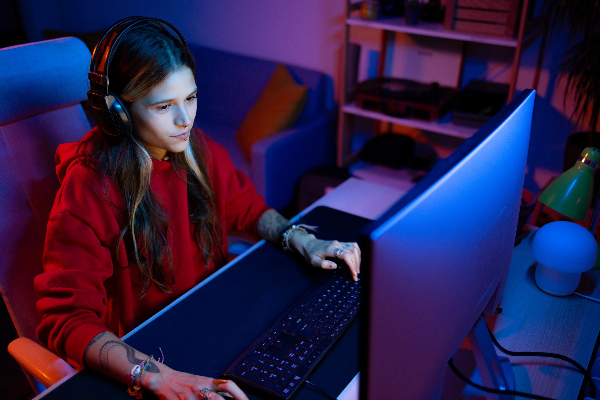 Young female gamer playing video games on desktop PC at home.